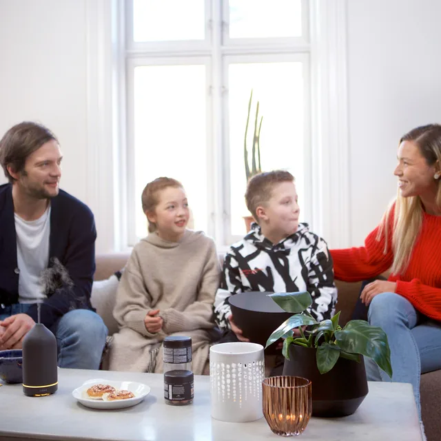 A family of four sitting together on a sofa, talking